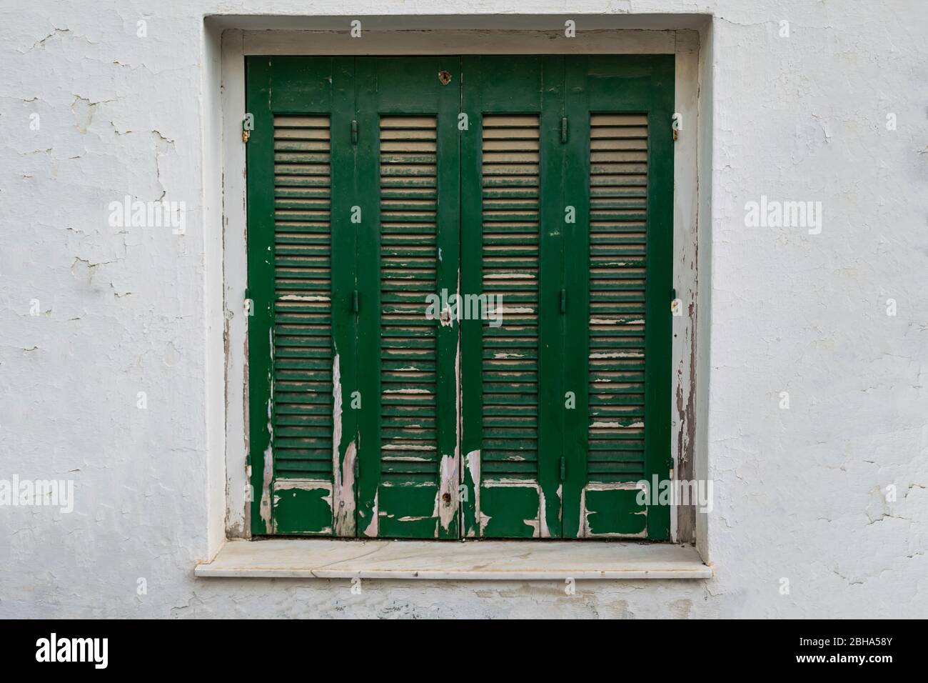 Old greek traditional green window shutters. Stock Photo