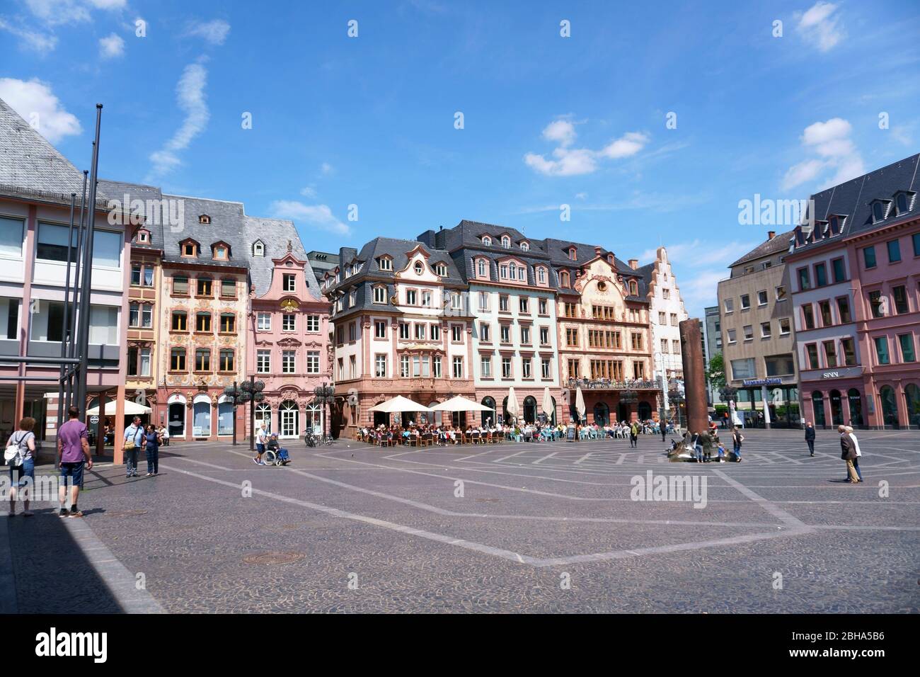In good weather, people sit outside of cafés in the market square with the Heunensäule in Mainz. Stock Photo