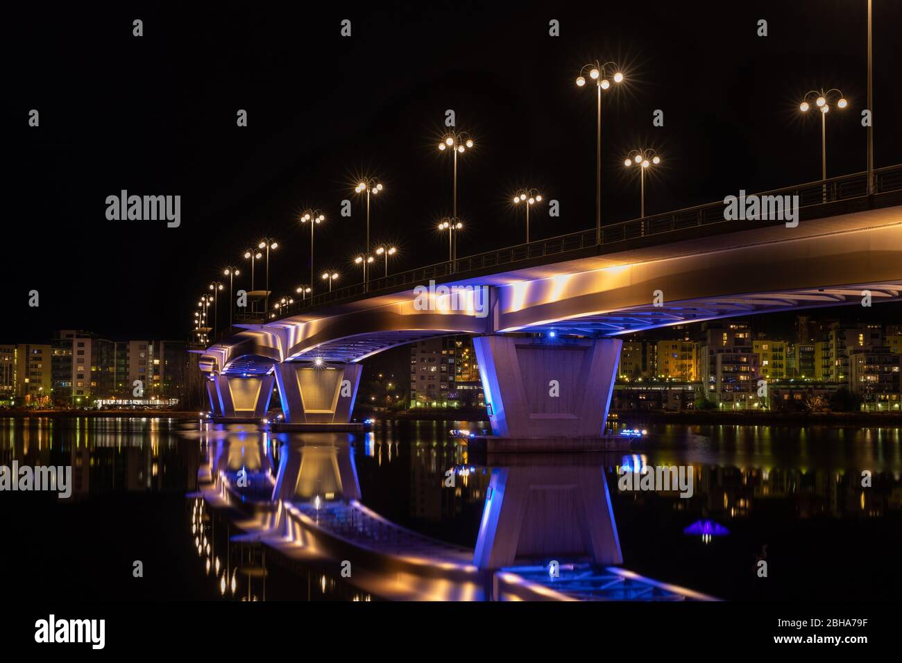 Illuminated bridge over still water with reflections Stock Photo