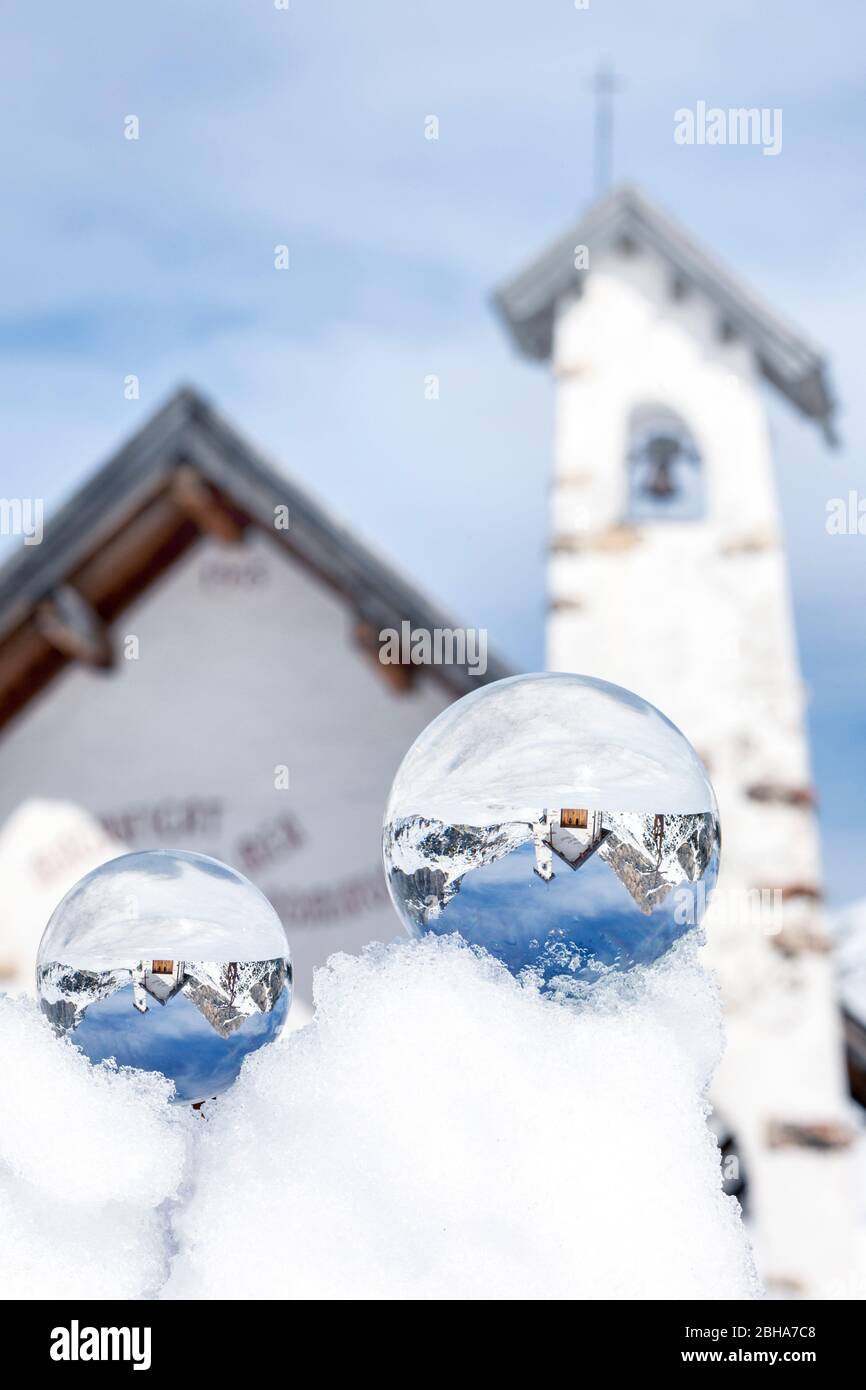 the alpine church at the falzarego pass in winter, reflected through a couple of crystal spheres, cortina d'ampezzo, belluno, veneto, italy Stock Photo