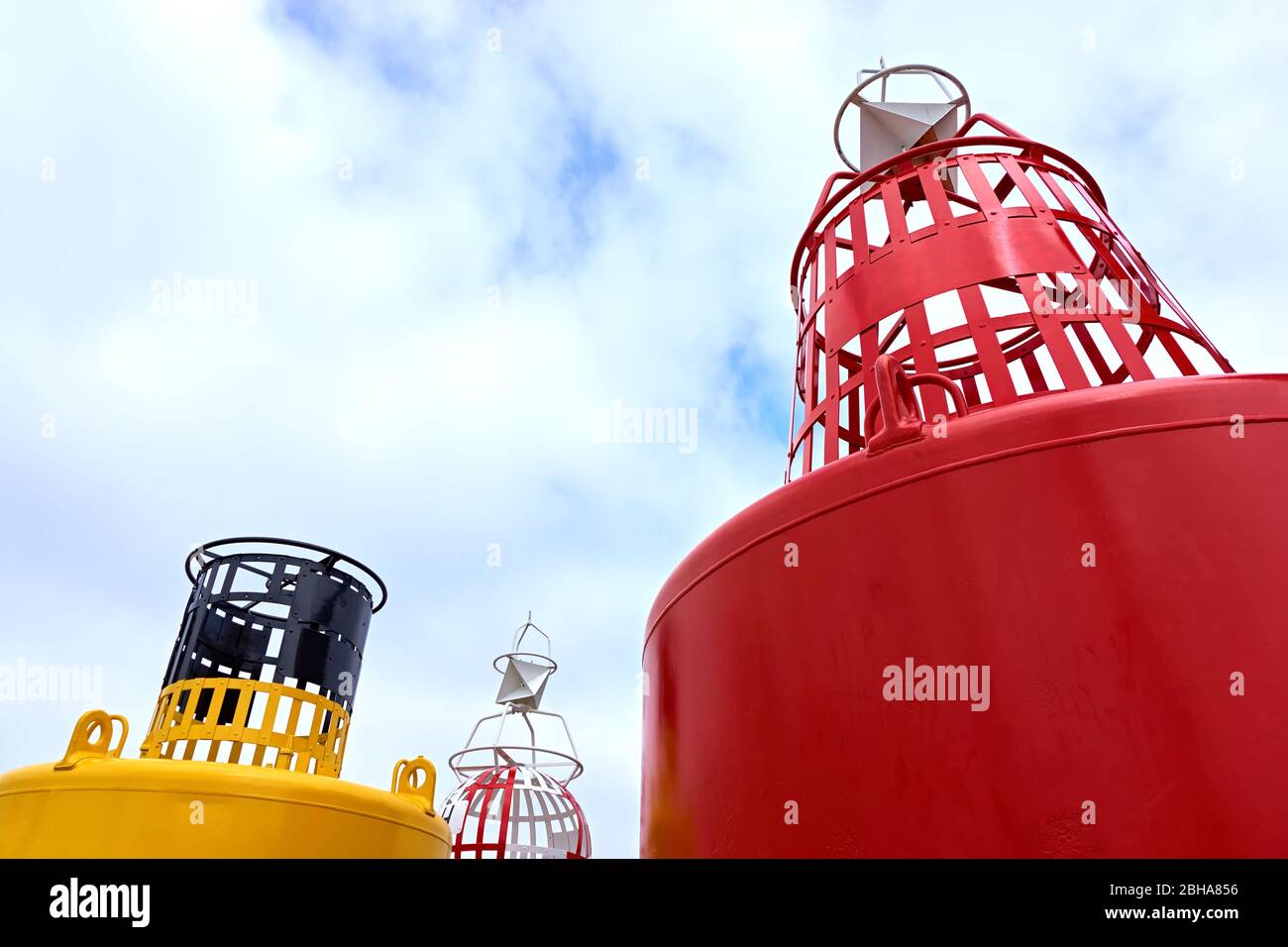 Large red and yellow buoy against a blue cloudy sky with copy space Stock Photo