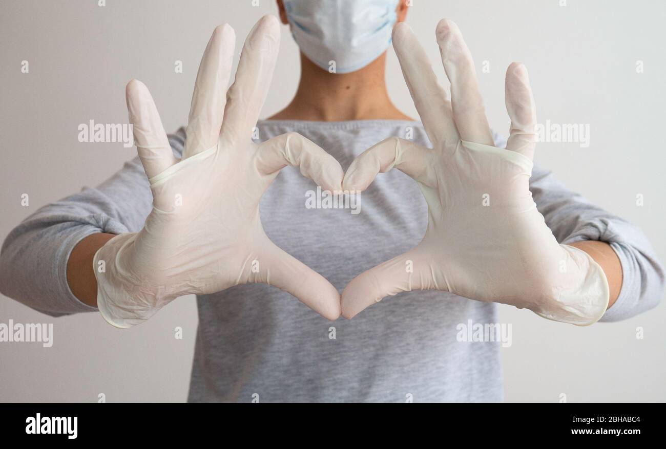 Woman with a medical mask and hands in latex white gloves shows the ...