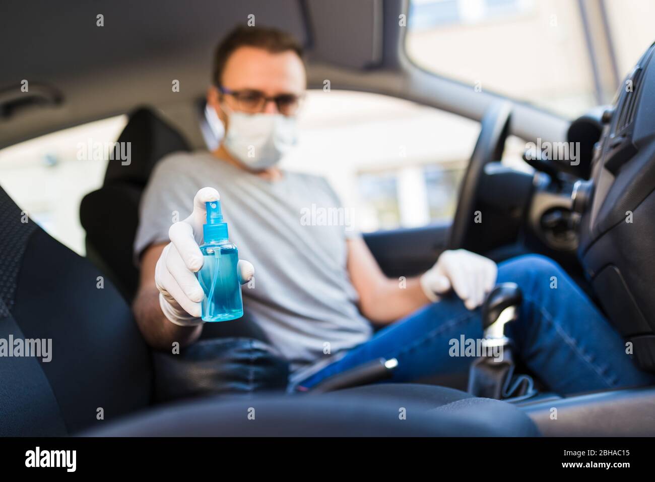 https://c8.alamy.com/comp/2BHAC15/driver-with-face-mask-and-medical-gloves-holding-disinfectant-spray-bottle-in-car-coronavirus-pandemic-concept-2BHAC15.jpg