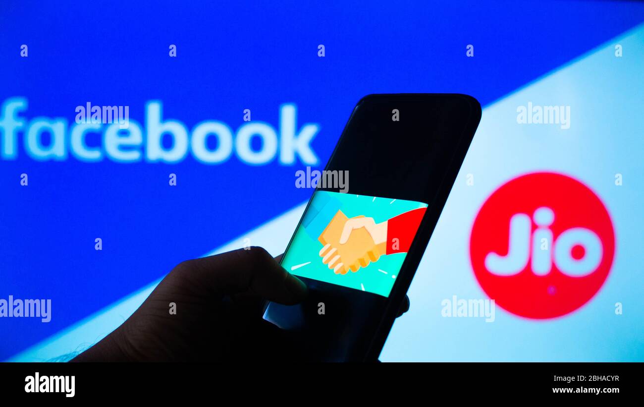 Jaipur, India, Circa 2020 - Photograph of a mobilephone with a handshake, signifying a deal, with facebook and Reliance jio in the background Stock Photo