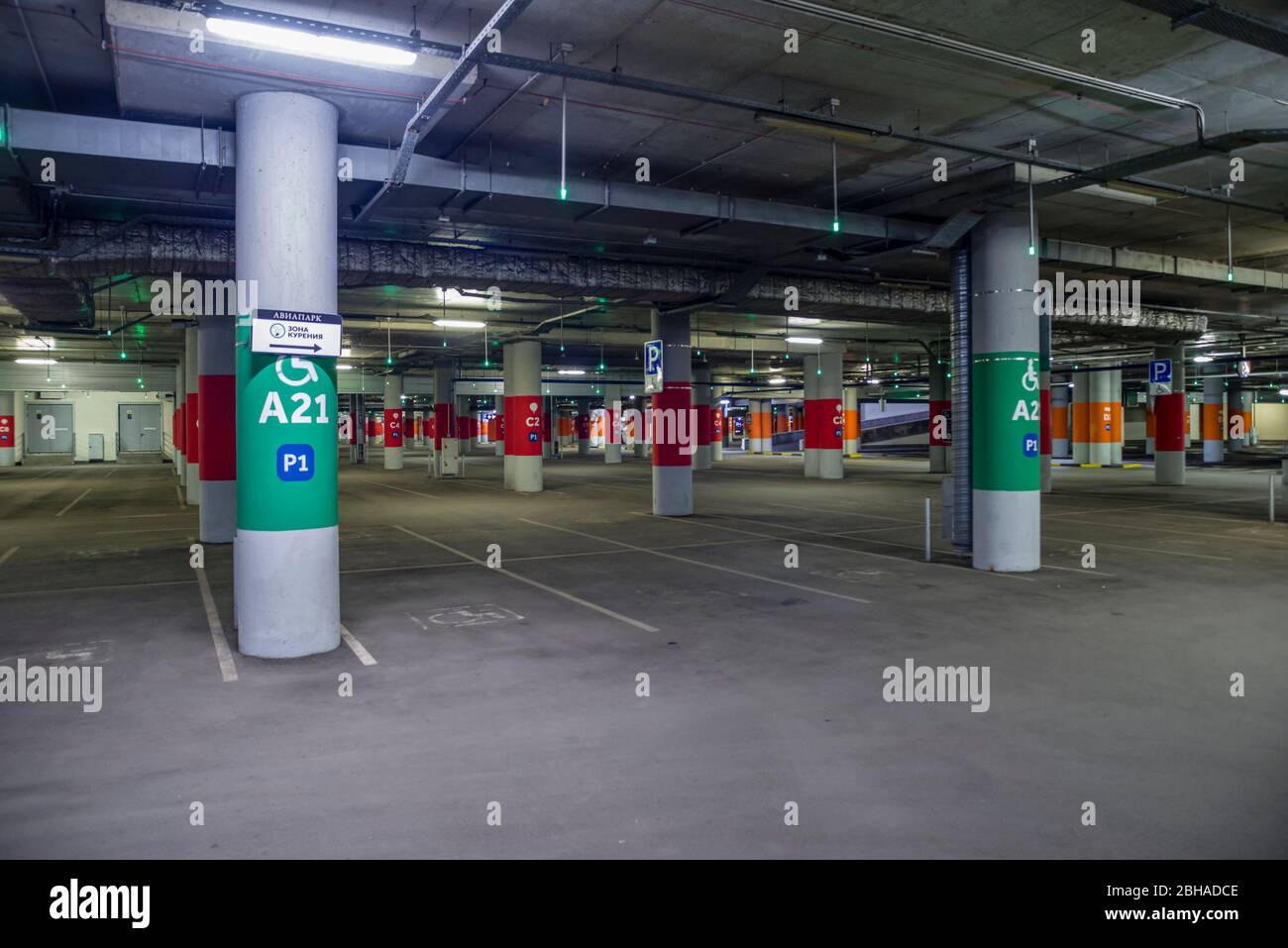 Moscow, Russia - April 22, 2020: Asphalt, dimly lit empty mall garage with ceiling lights. Stock Photo