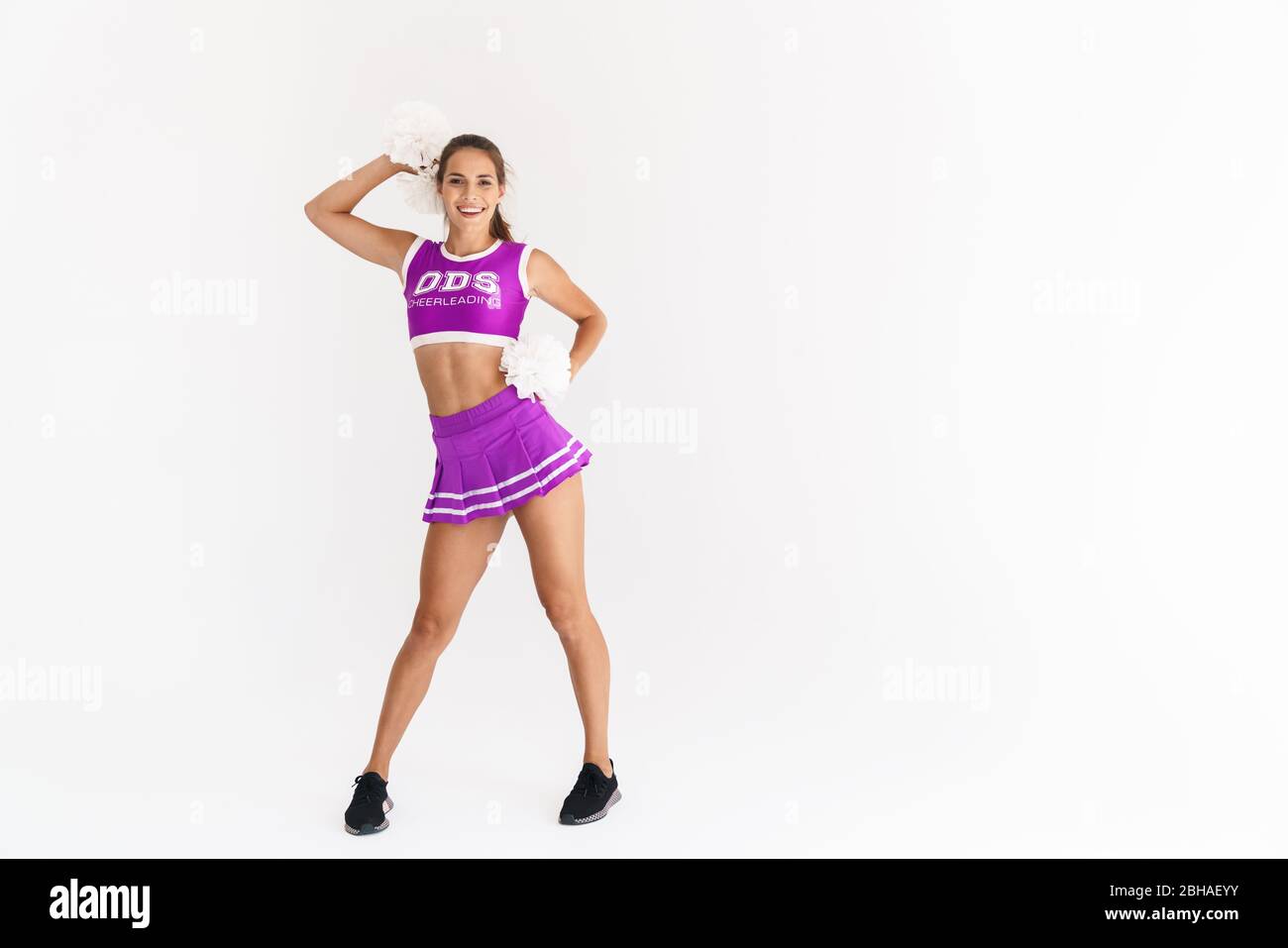 Portrait of smiling cheerleader woman dancing with pompoms isolated