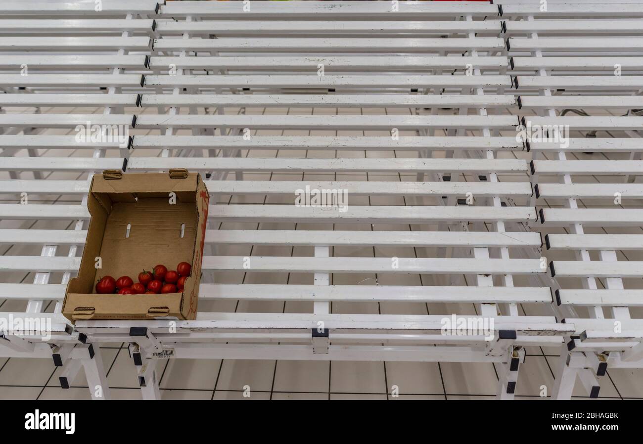 Moscow, Russia - April 22, 2020: Empty shelves with products in a chain grocery store. Half empty box with tomatoes. Stock Photo