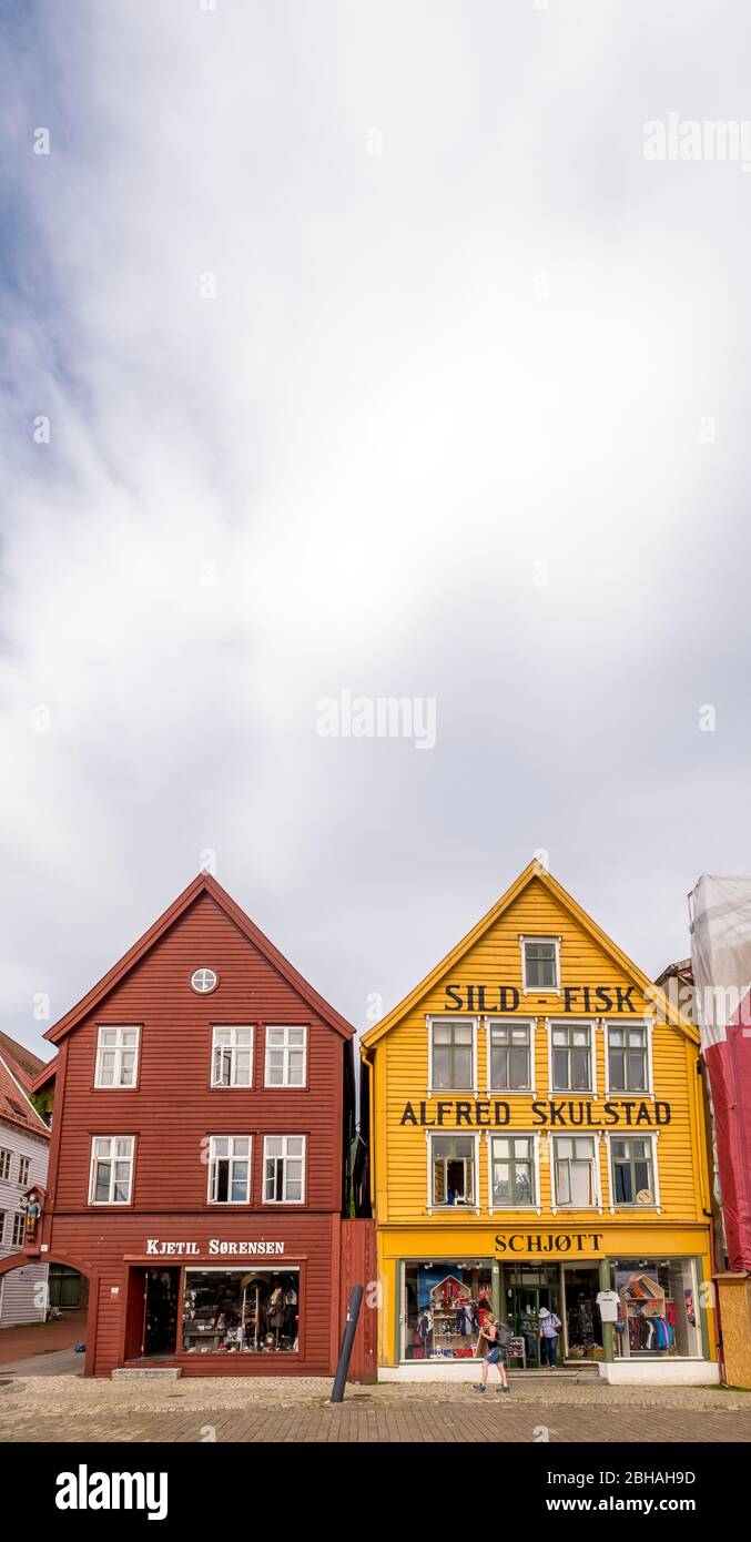 Tourists walk in front of the backdrop of colorful wooden houses with fashion shops in the Hanseatic quarter in Bryggen, Torget, The German Wharf, Bergen, Hordaland, Norway, Scandinavia, Europe Stock Photo