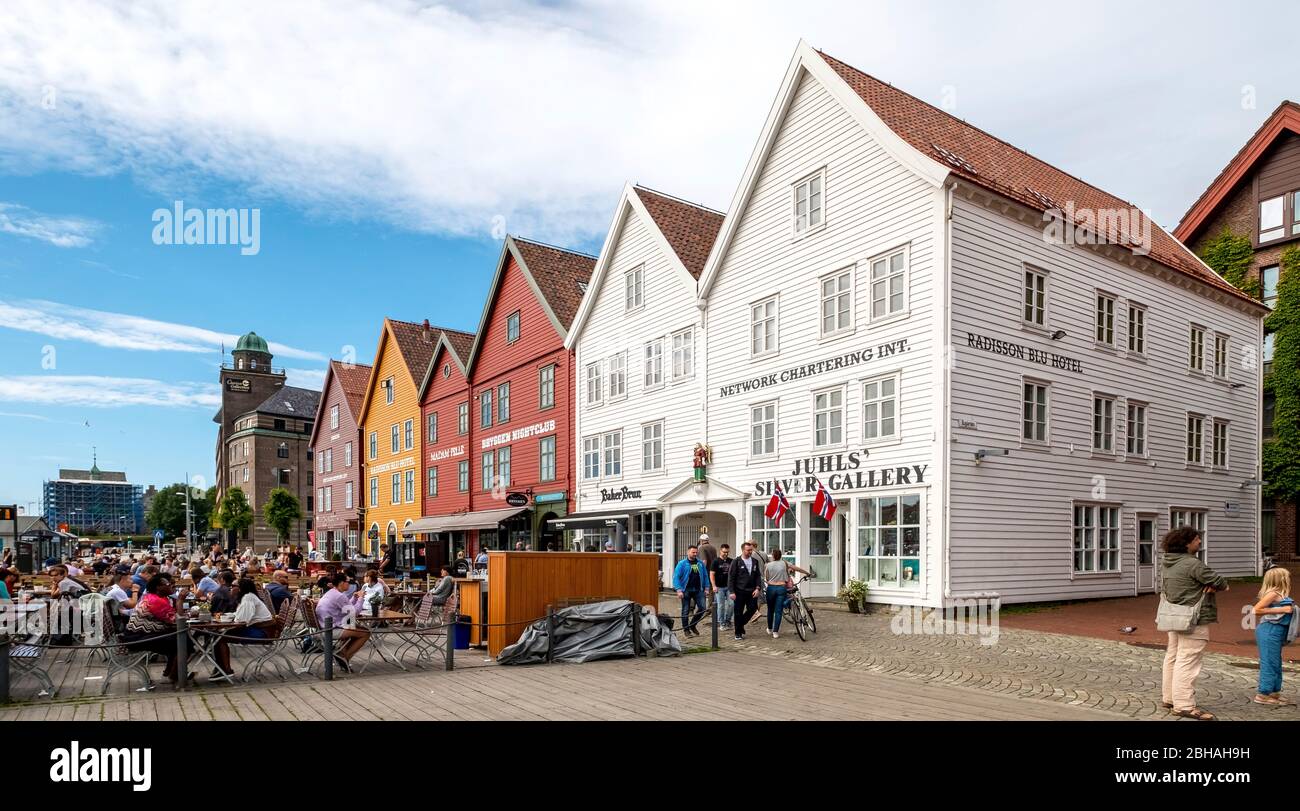 Tourists sit at tables against the historic backdrop of colorful wooden houses in Bryggen in the Hanseatic quarter of Bryggen, Torget, The German Wharf, Bergen, Hordaland, Norway, Scandinavia, Europe Stock Photo