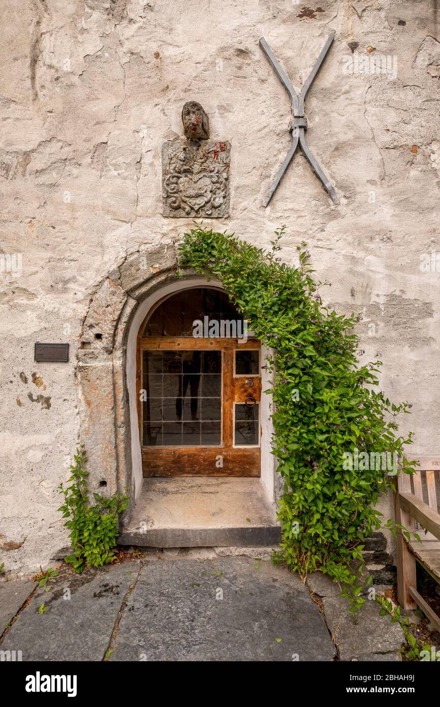 Stone house with romantic wooden entrance door with glass windows, decorated with an iron heart and an iron cross, bordered with ivy, Bryggen, Bergen, Hordaland, Norway, Scandinavia, Europe Stock Photo