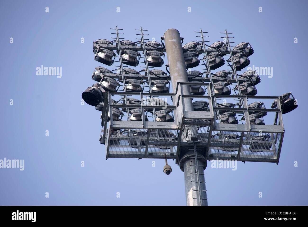The stadium floodlight of a large football stadium with many small lamps and in front of a blue sky with clouds. Stock Photo