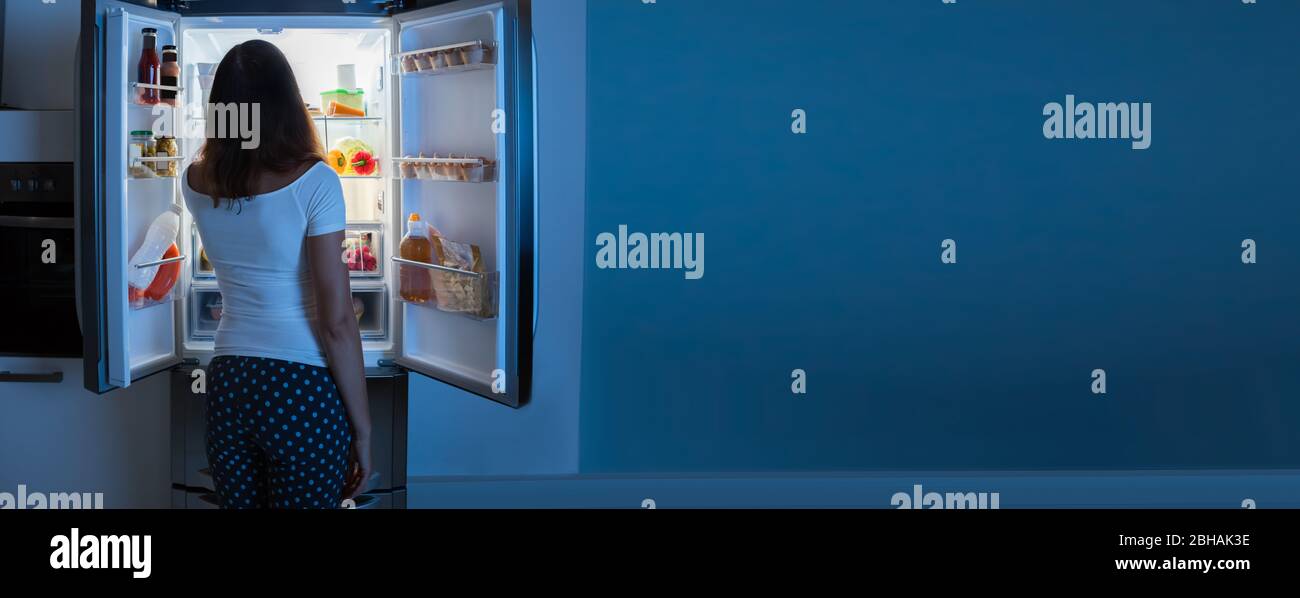 Hungry Person Eating Food From Fridge At Night Stock Photo