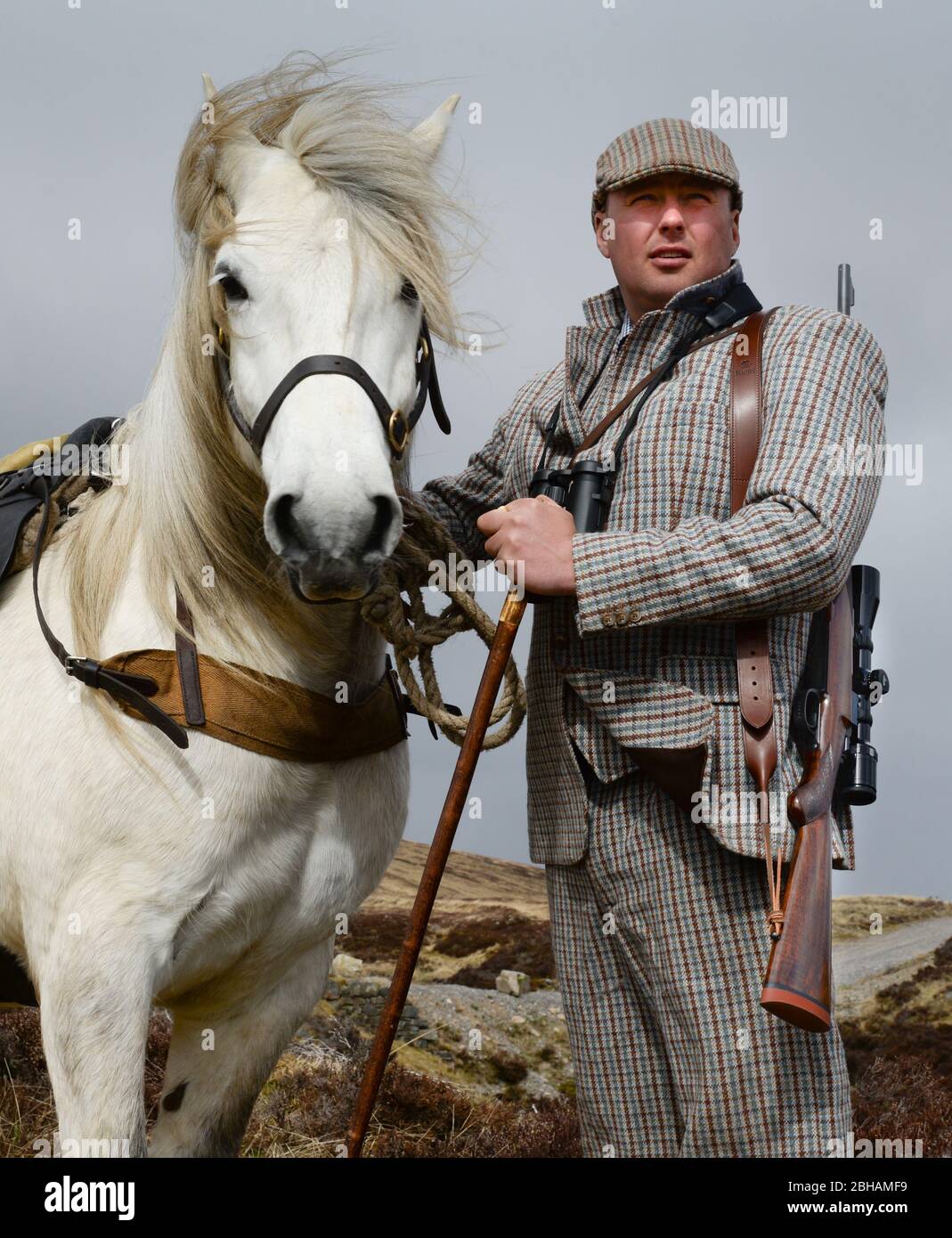 Atholl Estate Gamekeeper with a Rigby rifle with telescopic sight with a highland pony used to carry deer of the hills Stock Photo