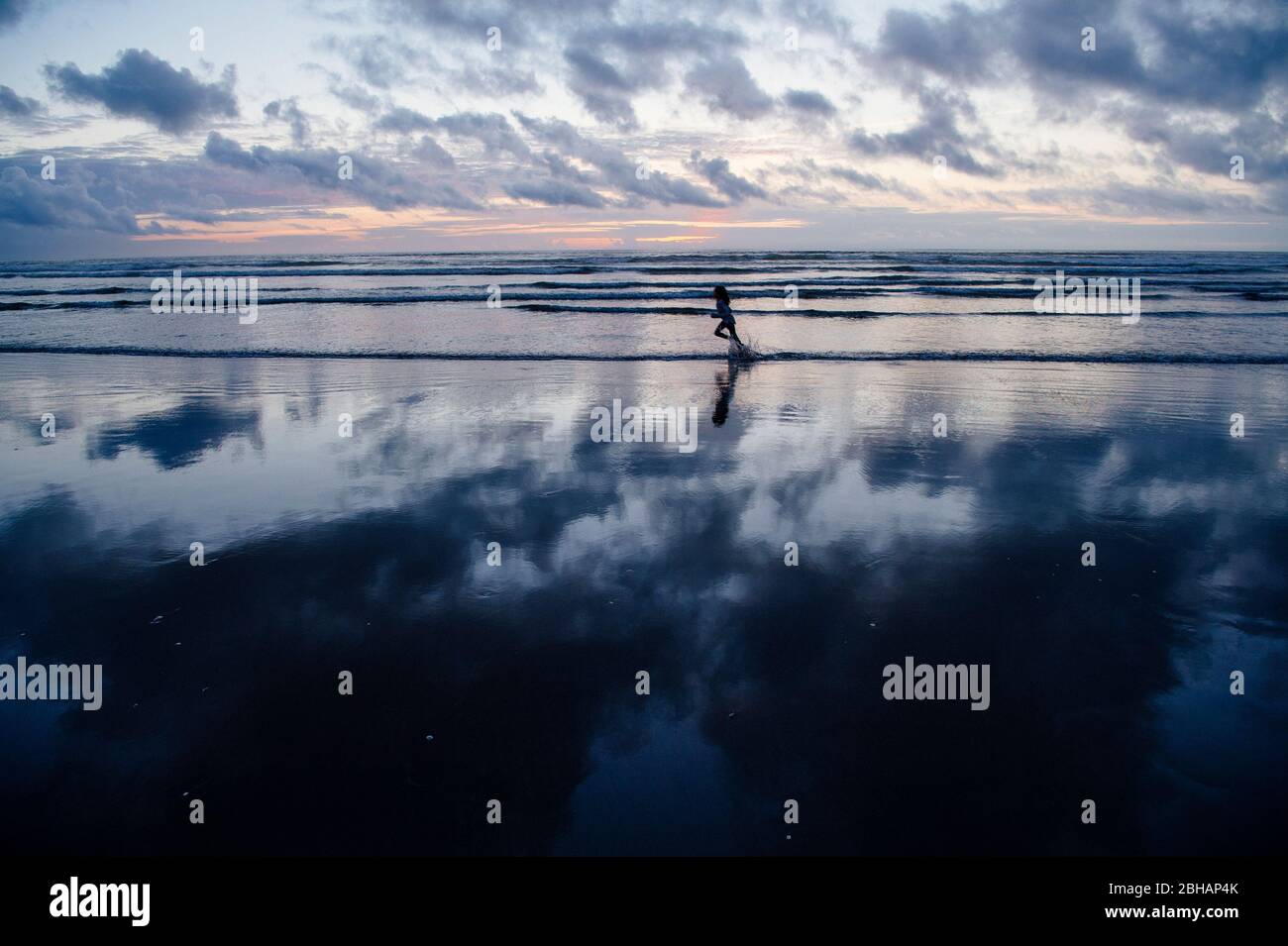 Girl running on beach at sunset, Seaside, Oregon, USA Stock Photo