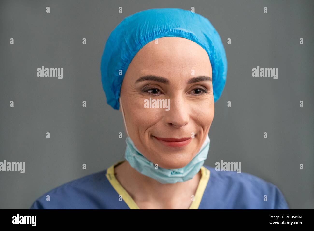Smiling Doctor Taking Off Her Protective Mask Stock Photo