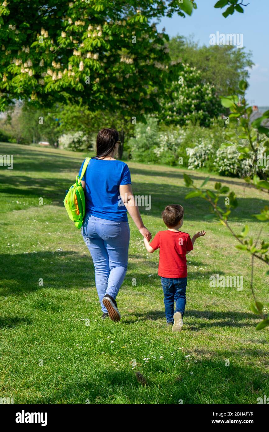 A mother and son walking holding hands outside in spring Stock Photo