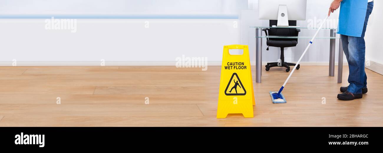 Janitor Cleaning Office Floor With Healthcare Disinfectant Stock Photo