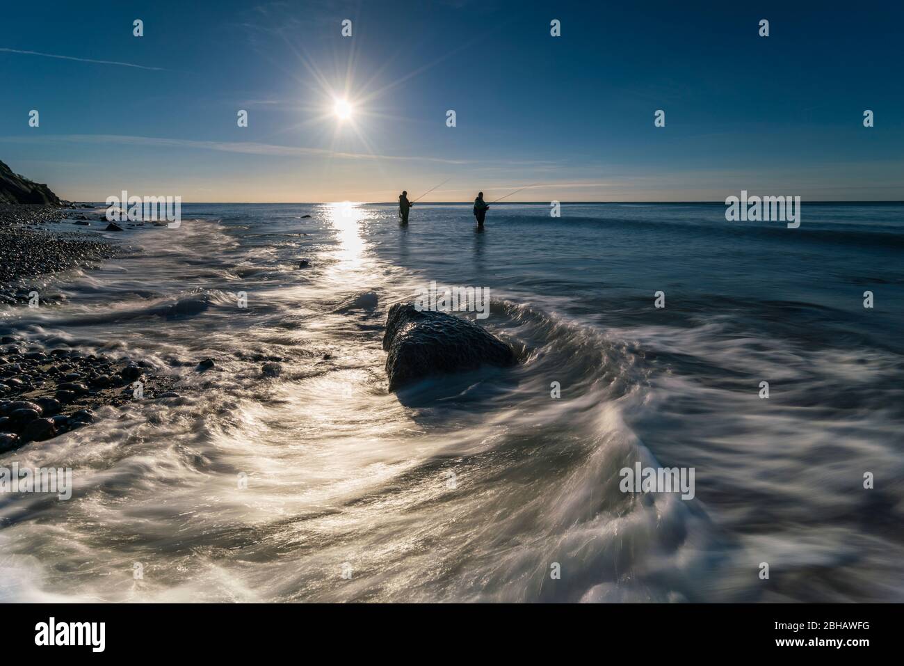 Ostsee im strahlenden Gegenlicht und Angler am Ufer Stock Photo