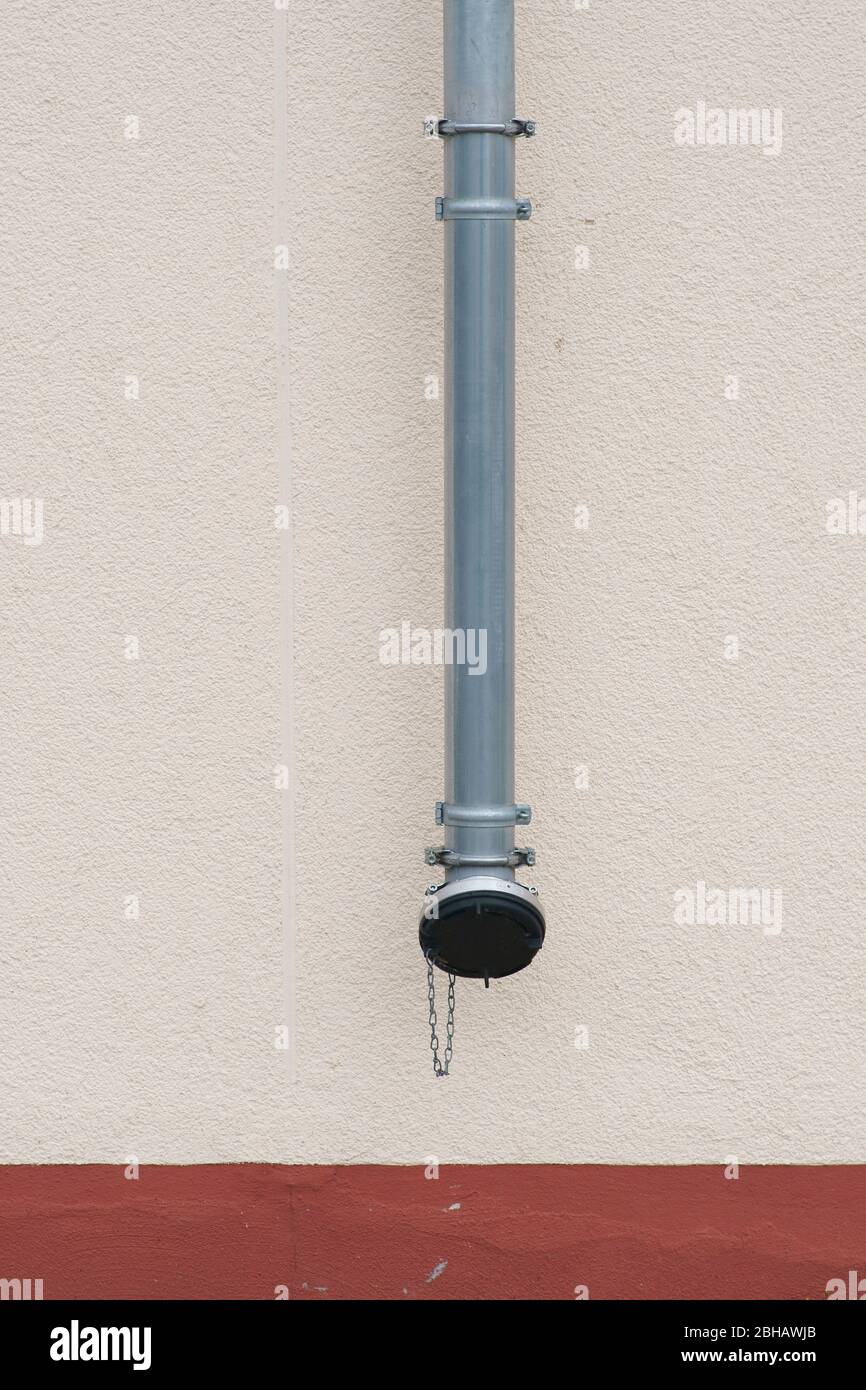 A new rain pipe on a new exterior wall made of plaster. Stock Photo