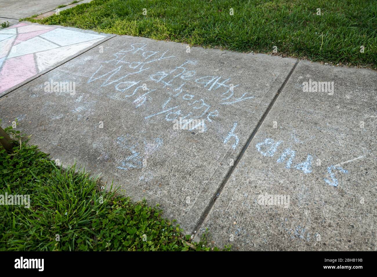 Children's messages written in sidewalk chalk reminding people to wash their hands during the Covid-19 Pandemic. Stock Photo