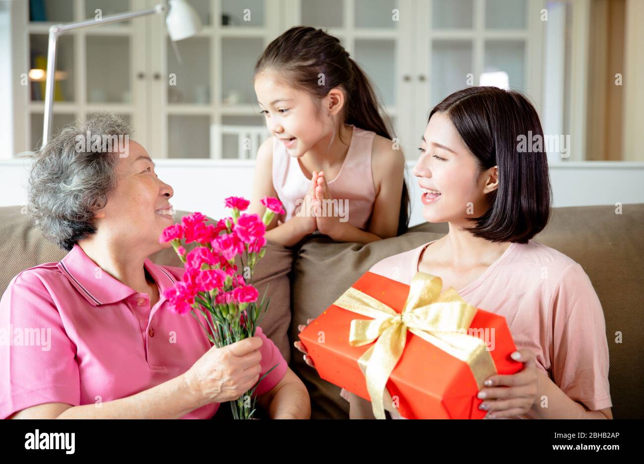 Happy mother's day . Child and mother congratulating grandmother giving her flowers and gift box