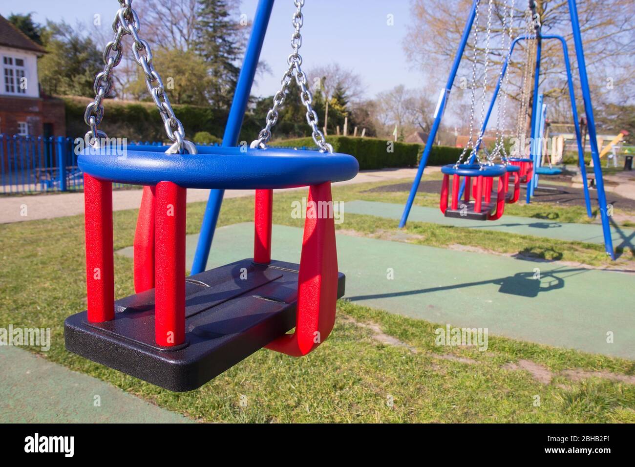 Empty swings in children's playground in England due to coronavirus quarantine for the prevention of COVID-19. Stock Photo