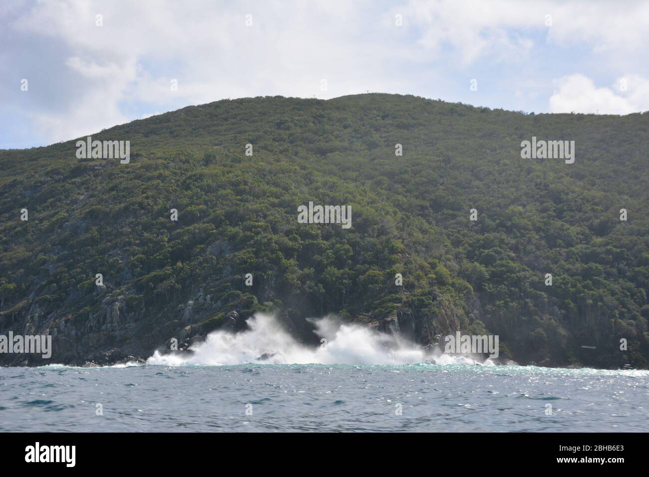 Waves crash against a thickly forested island in the British Virgin Islands, a British Overseas Territory in the Caribbean. Stock Photo