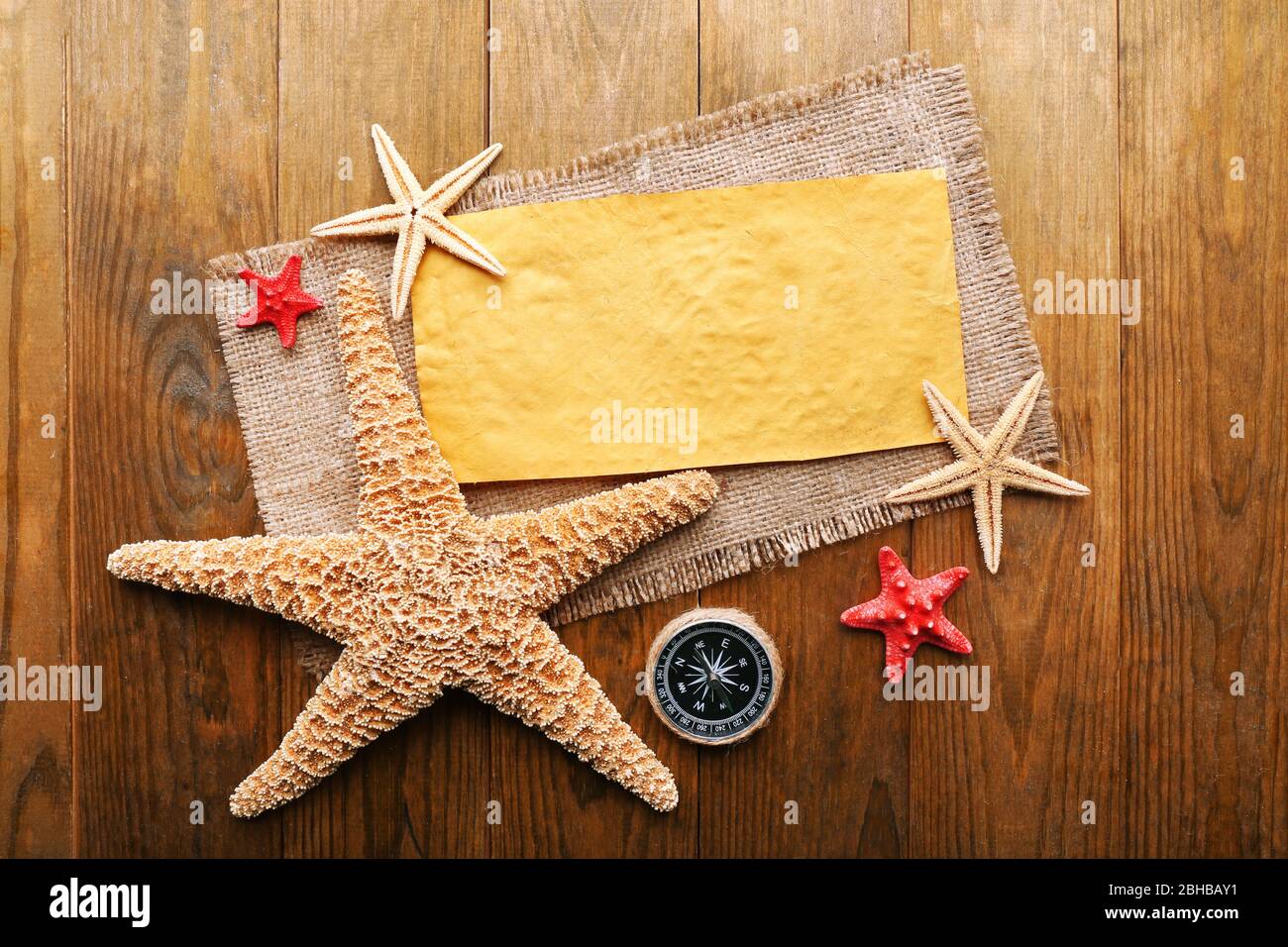 Card blank with sea stars and compass on wooden background Stock Photo