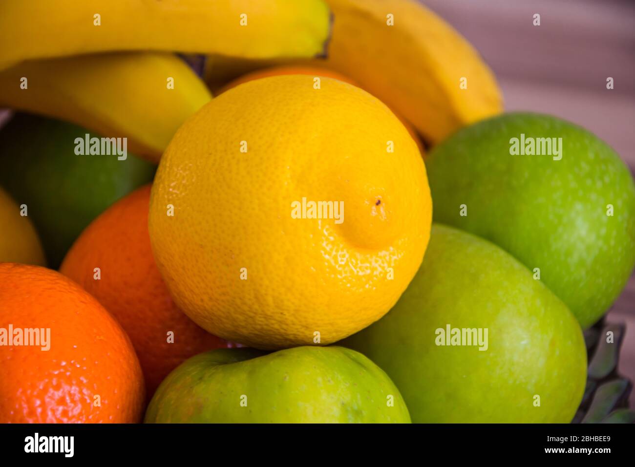 Close up of a big yellow lemon between apples oranges and other fruits ...