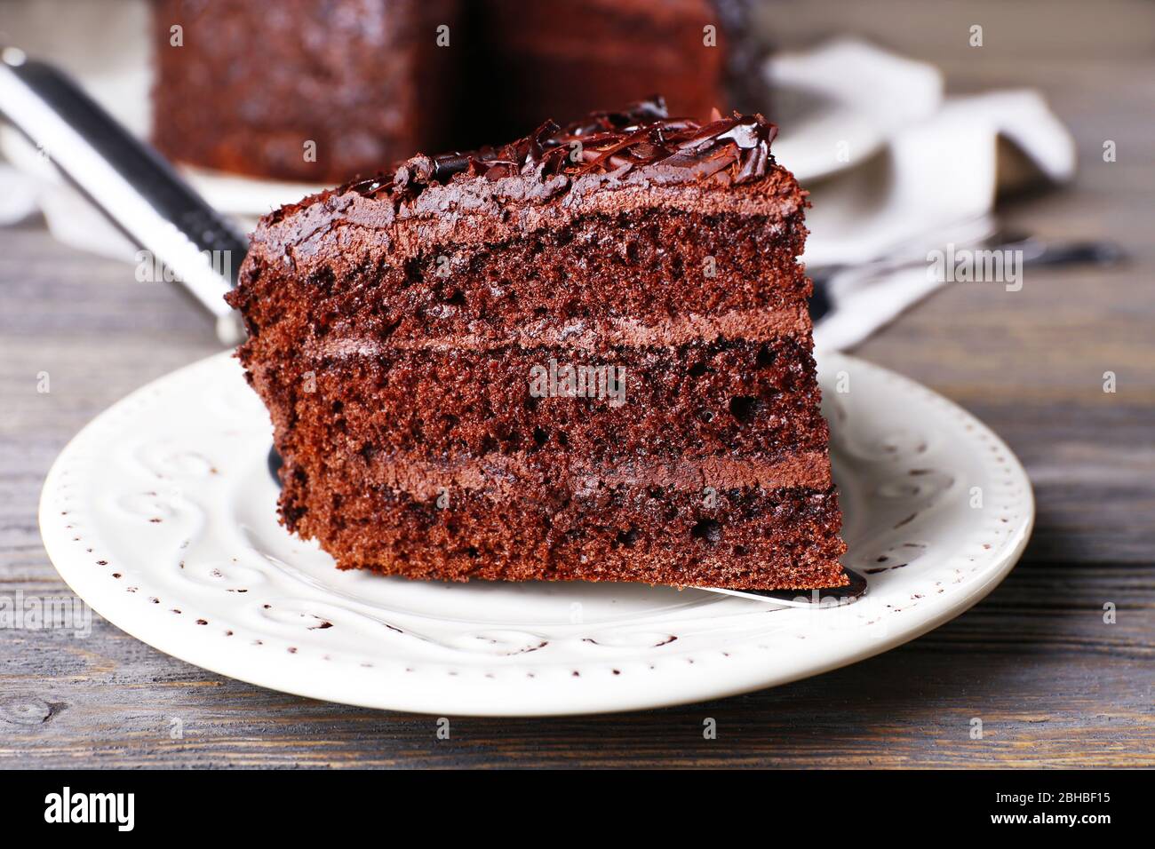 Delicious chocolate cake in white plate on wooden table background ...