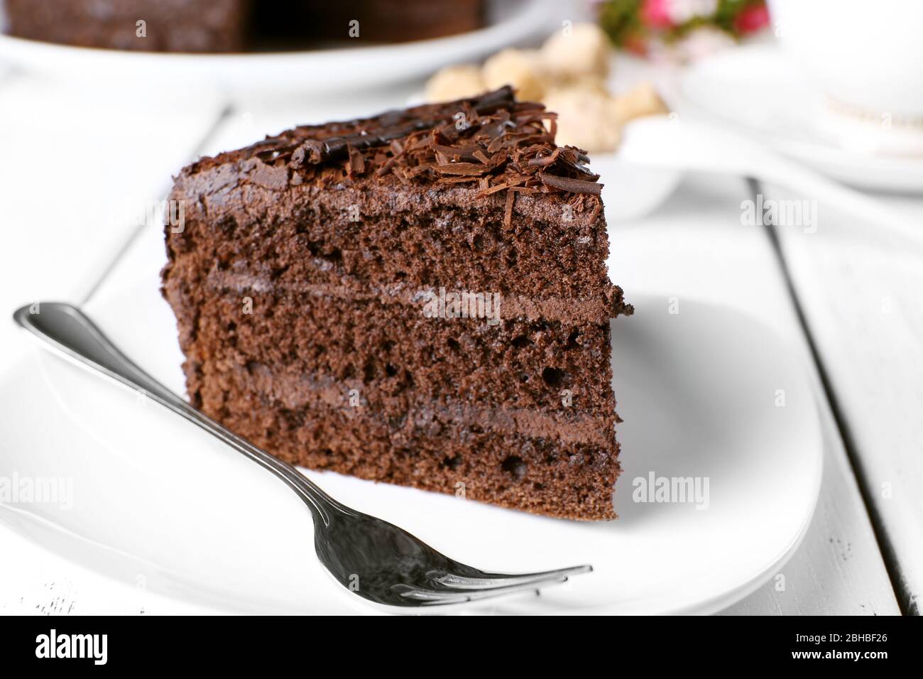 Piece of delicious chocolate cake in plate with fork on color wooden ...