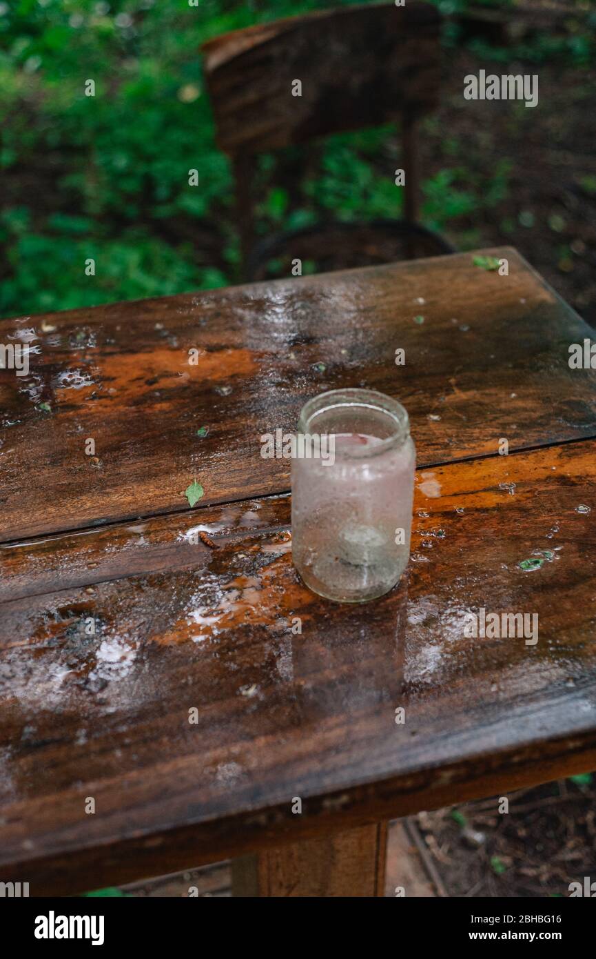 Empty jar on a wet wooden table in a garden. Rain soaked garden table