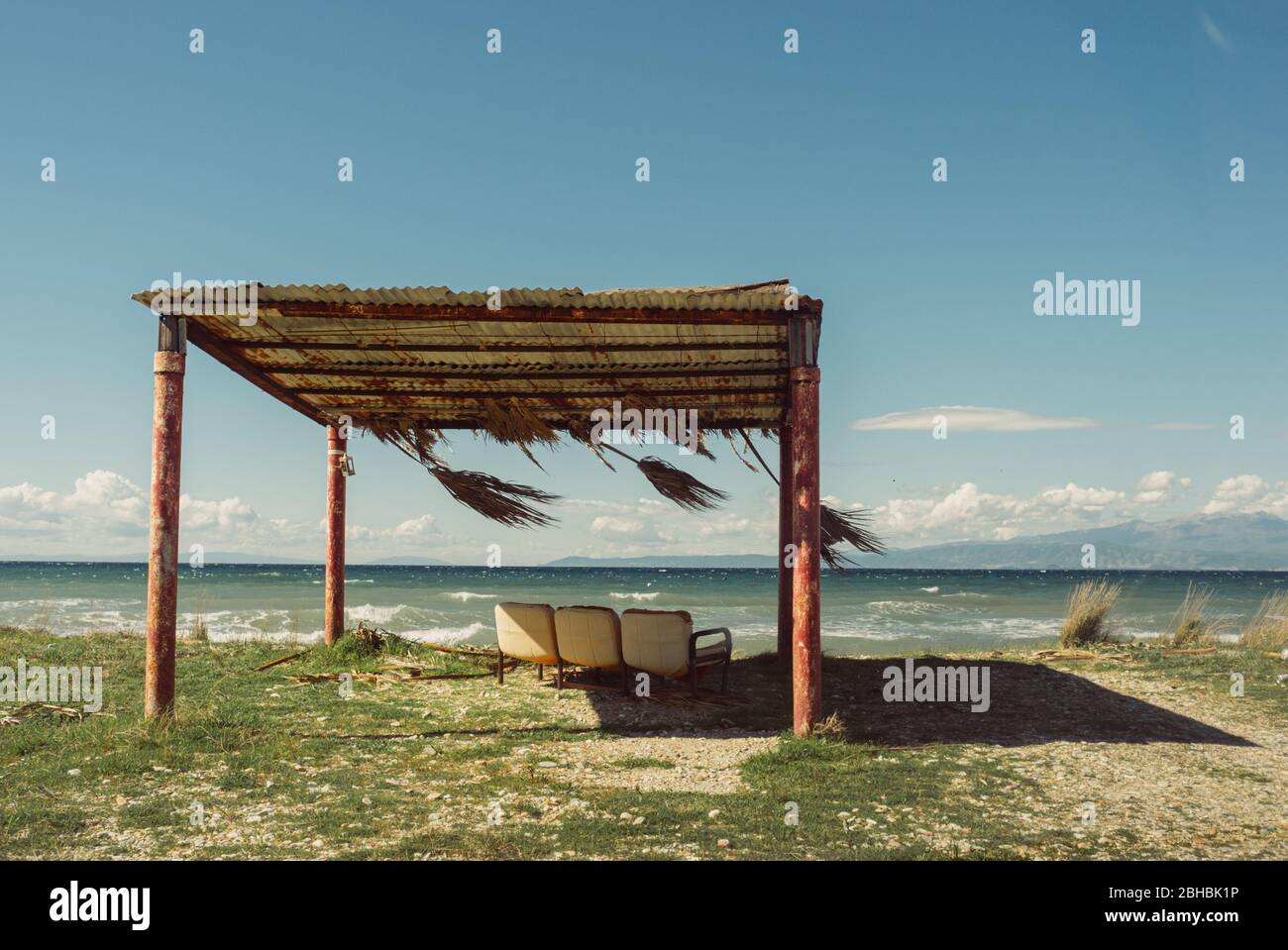 Three empty beach chairs under rustic beach tent on an empty beach in Thassos, Greece Stock Photo