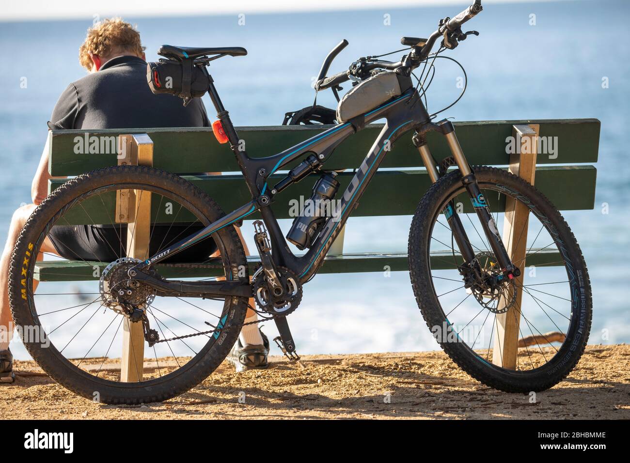 Australian man takes a rest from riding his scott mountain bike bicycle by a Sydney beach,NSW,Australia Stock Photo
