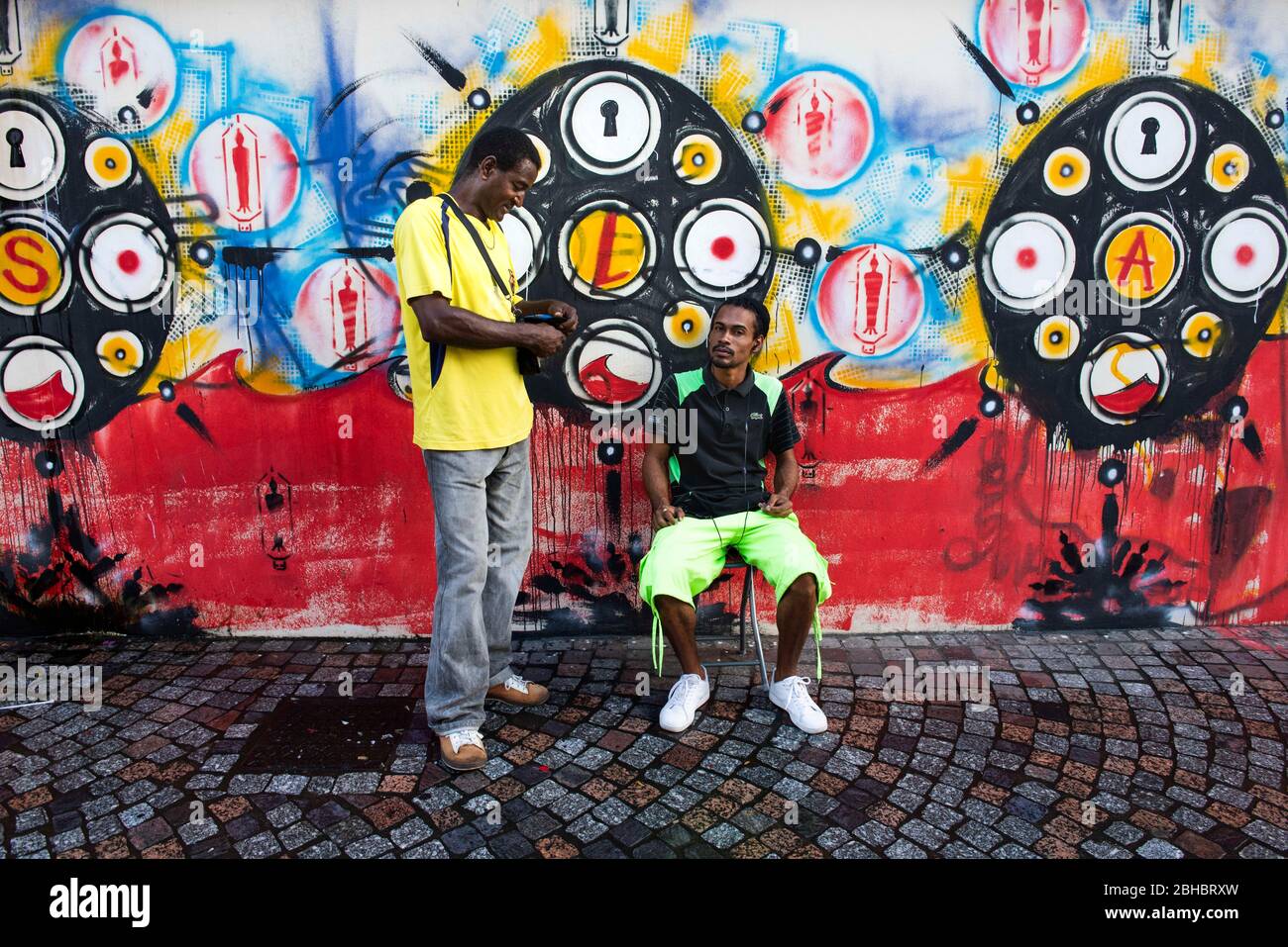 Caribbean, Lesser Antilles, Martinique Island. Men in front of mural