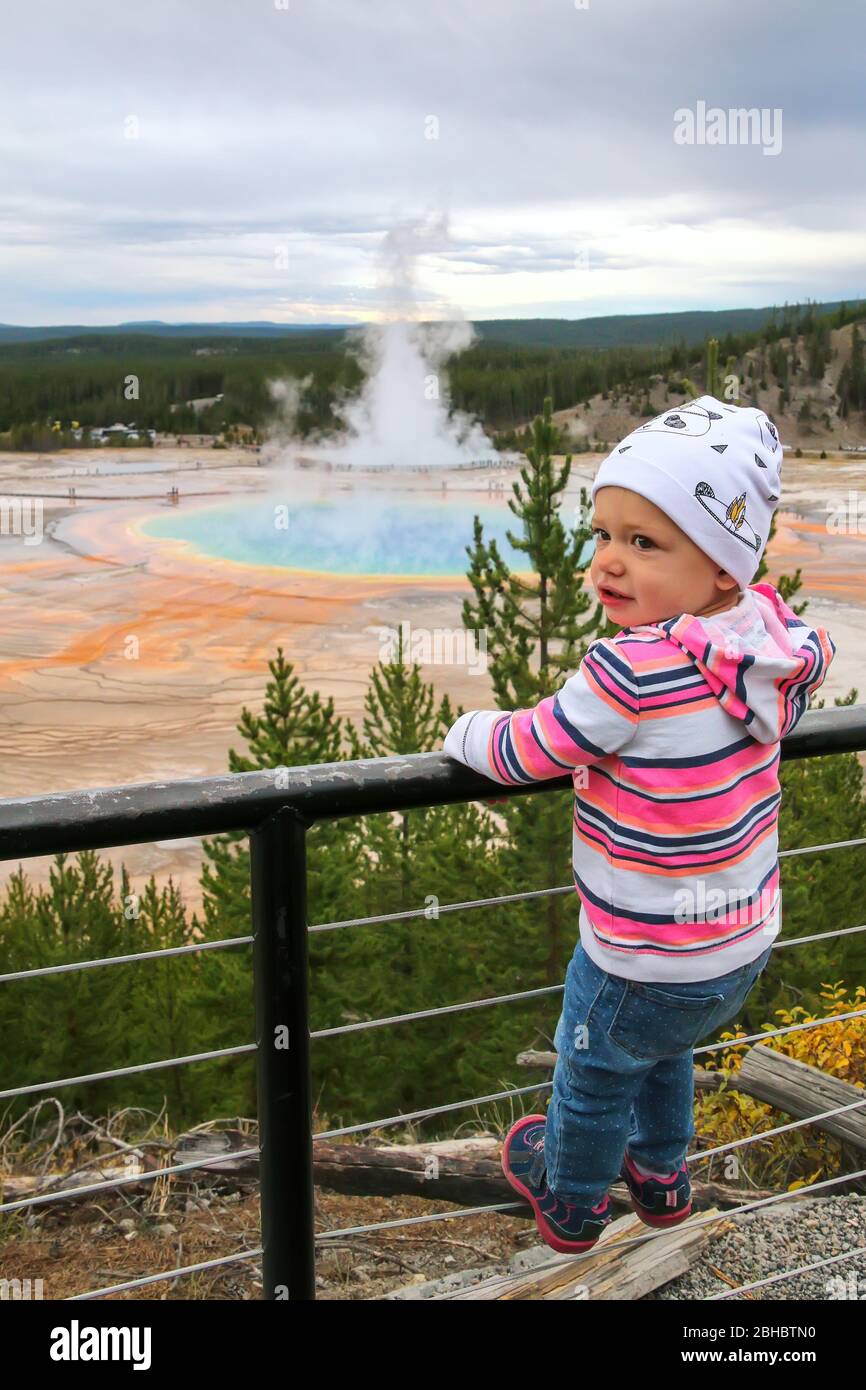Toddler girl standing at Grand Prismatic Spring overlook, Midway Geyser Basin, Yellowstone National Park, Wyoming, USA. It is the largest hot spring i Stock Photo