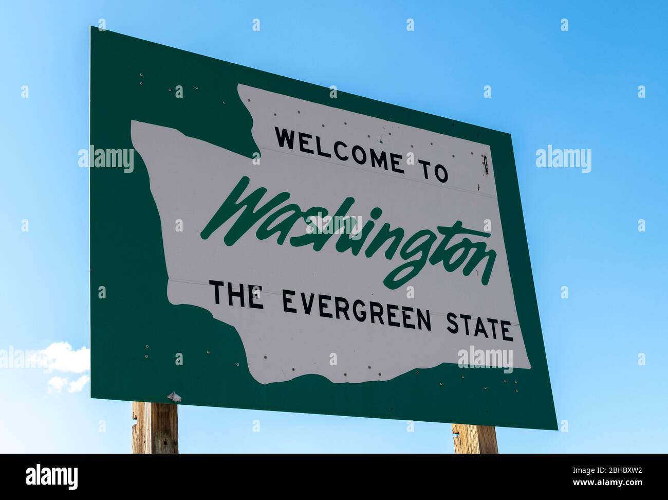 A roadside sign with welcome to Washington State, the evergreen state written on it with a blue sky behind. Stock Photo