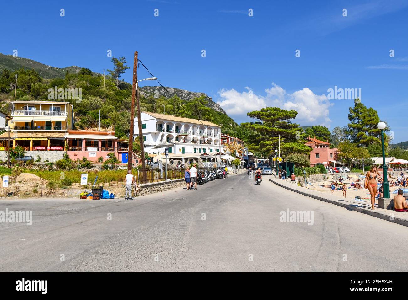 The beachfront Mediterranean village of Palaiokastritsa on the island of Corfu, Greece, in the Ionian Sea, on a summer day filled with tourists. Stock Photo