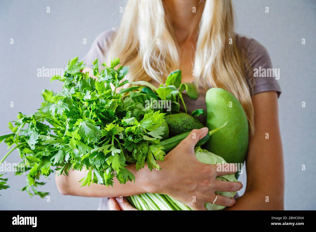 Young slim woman with blonde hair holding fresh green vegetables and fruits: celery, cucumber, mango, lime, cabbage at home. Healthy lifestyle during Stock Photo - Alamy Young slim woman with blonde hair holding fresh green vegetables and fruits: celery, cucumber, mango, lime, cabbage at home. Healthy lifestyle during Stock Photo - Alamy