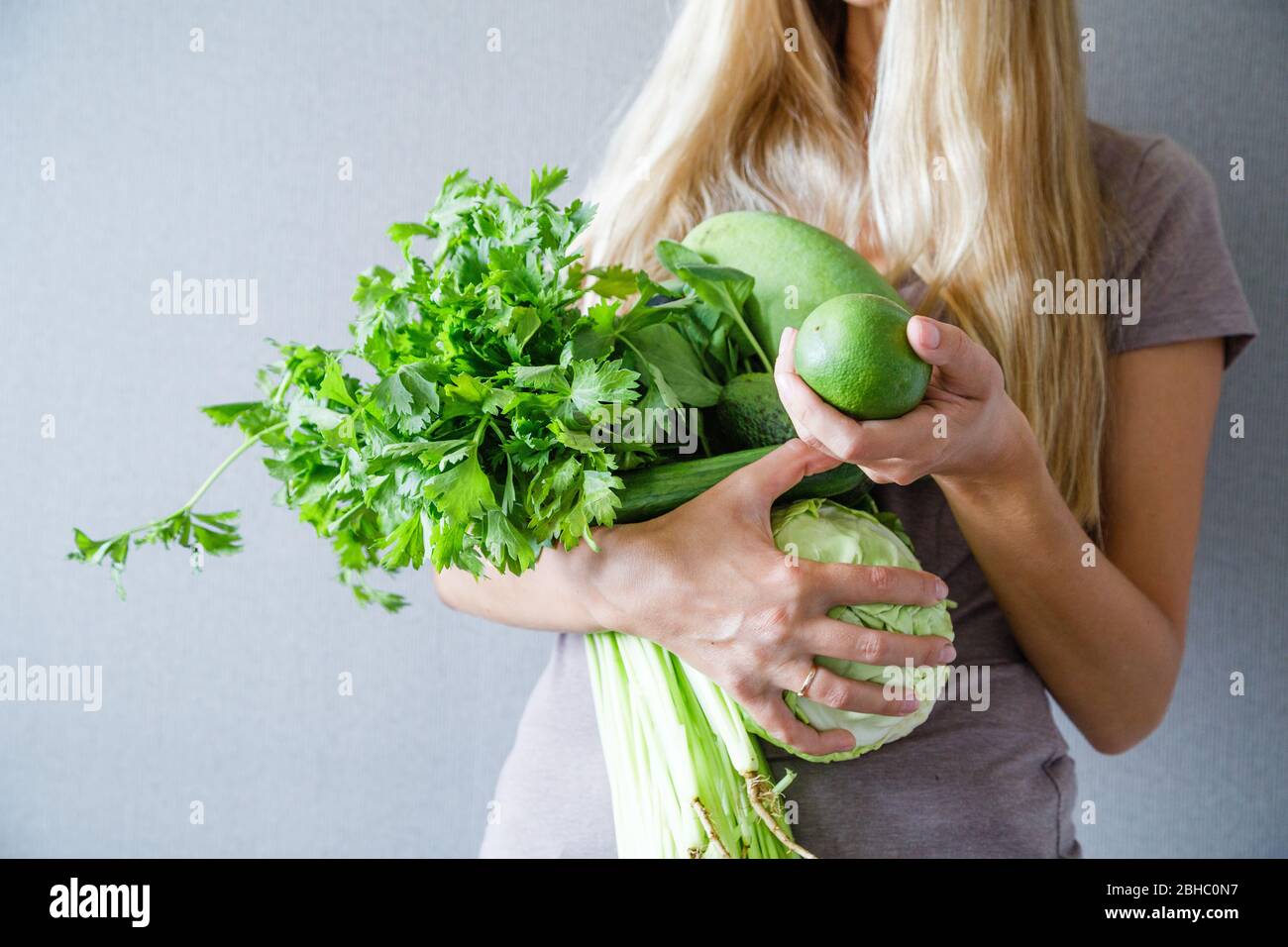 Young slim woman with blonde hair holding fresh green vegetables and fruits: celery, cucumber, mango, lime, cabbage at home. Healthy lifestyle during Stock Photo - Alamy Young slim woman with blonde hair holding fresh green vegetables and fruits: celery, cucumber, mango, lime, cabbage at home. Healthy lifestyle during Stock Photo - Alamy