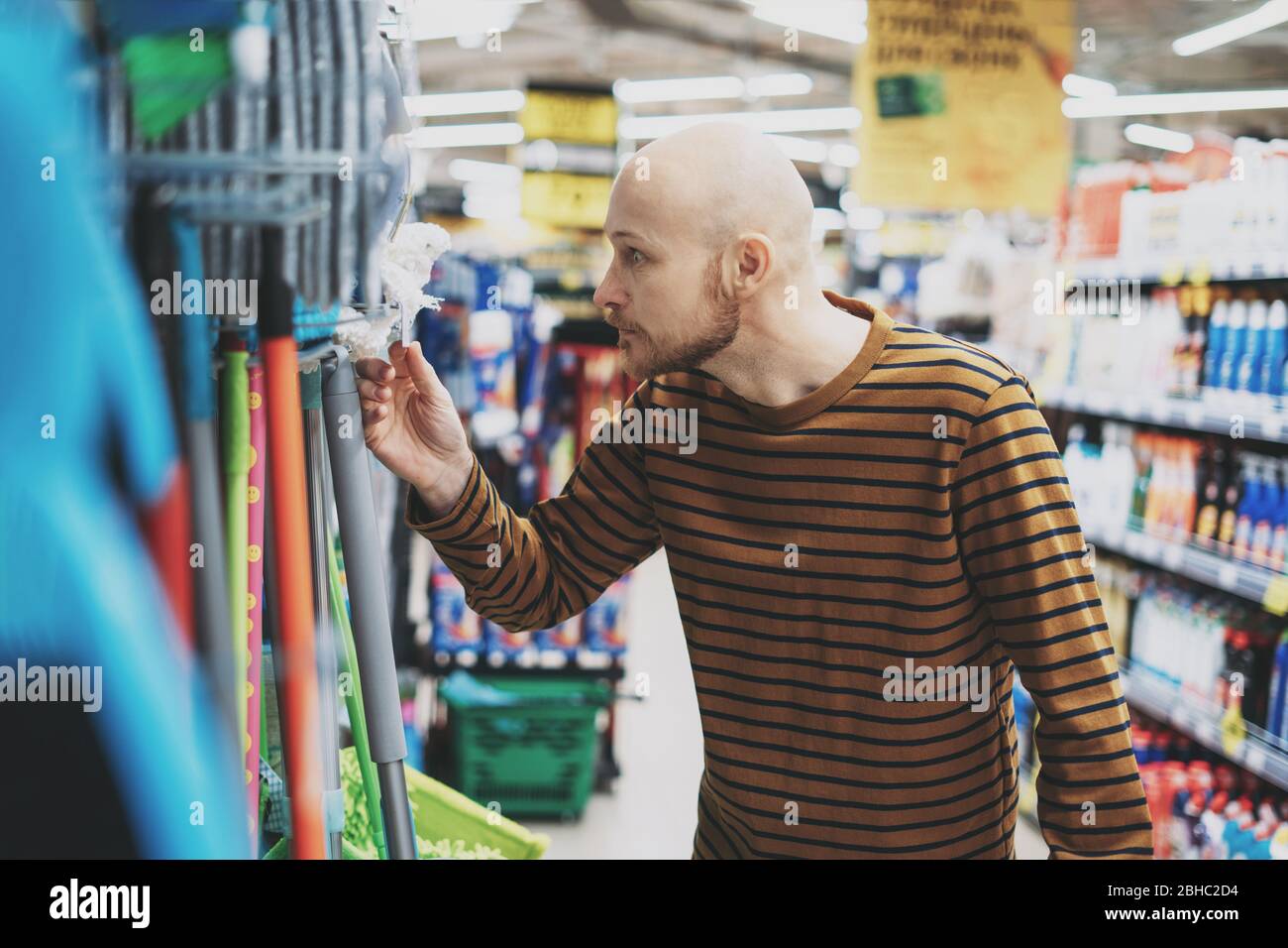 Adult bald bearded man shocked by price in hardware department of supermarket Stock Photo