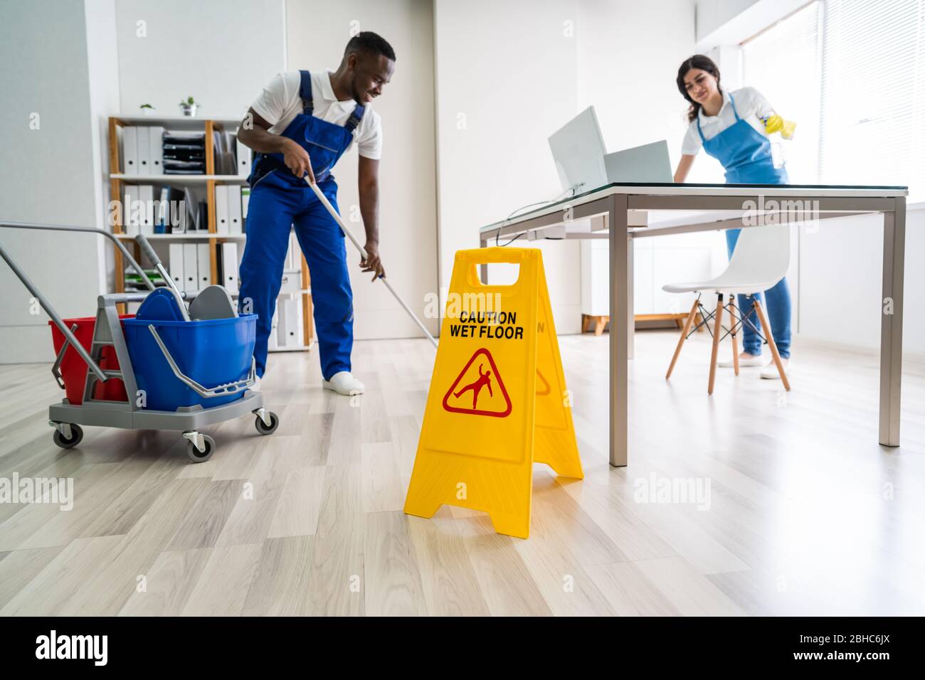 Young Male And Female Cleaners Cleaning Office Stock Photo