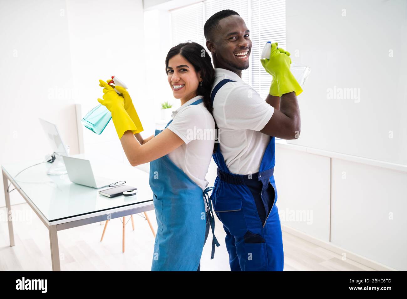 Two Janitors Standing Back To Back In Office Stock Photo