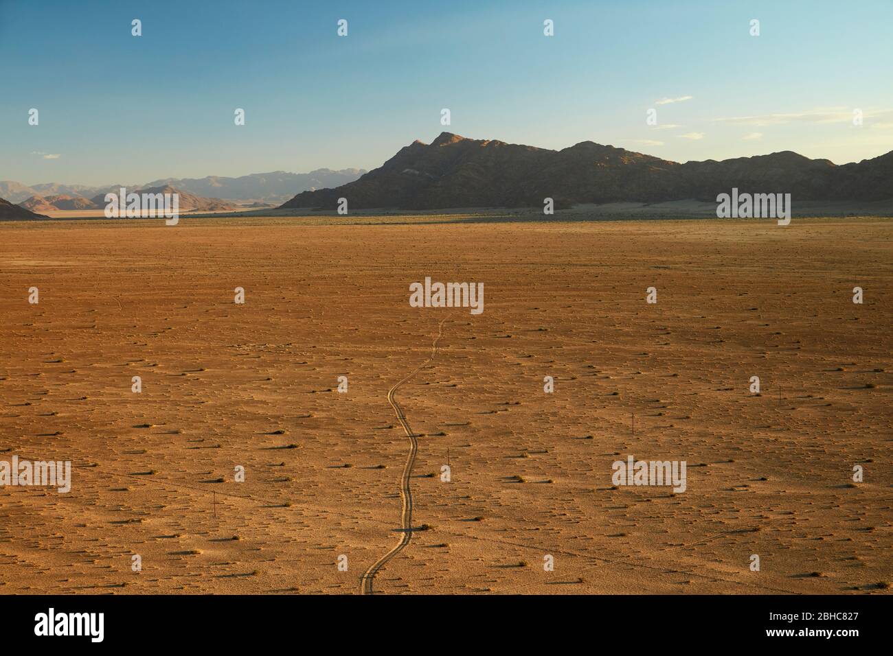 View of track across plain and mountains from high on a rock koppie above Desert Camp, Sesriem, Namib Desert, Namibia, Africa Stock Photo