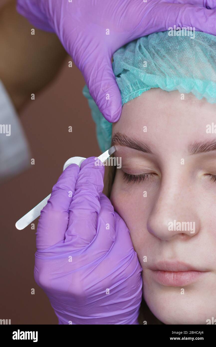 Eyebrow correction with tweezers. Final stage of creating perfect shape