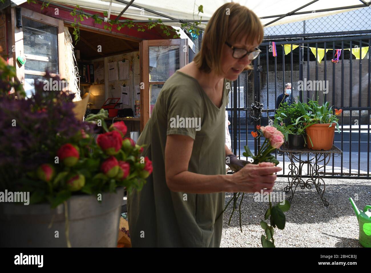 A man wearing a masks looks in as florist Sam Hartley makes a bouquet