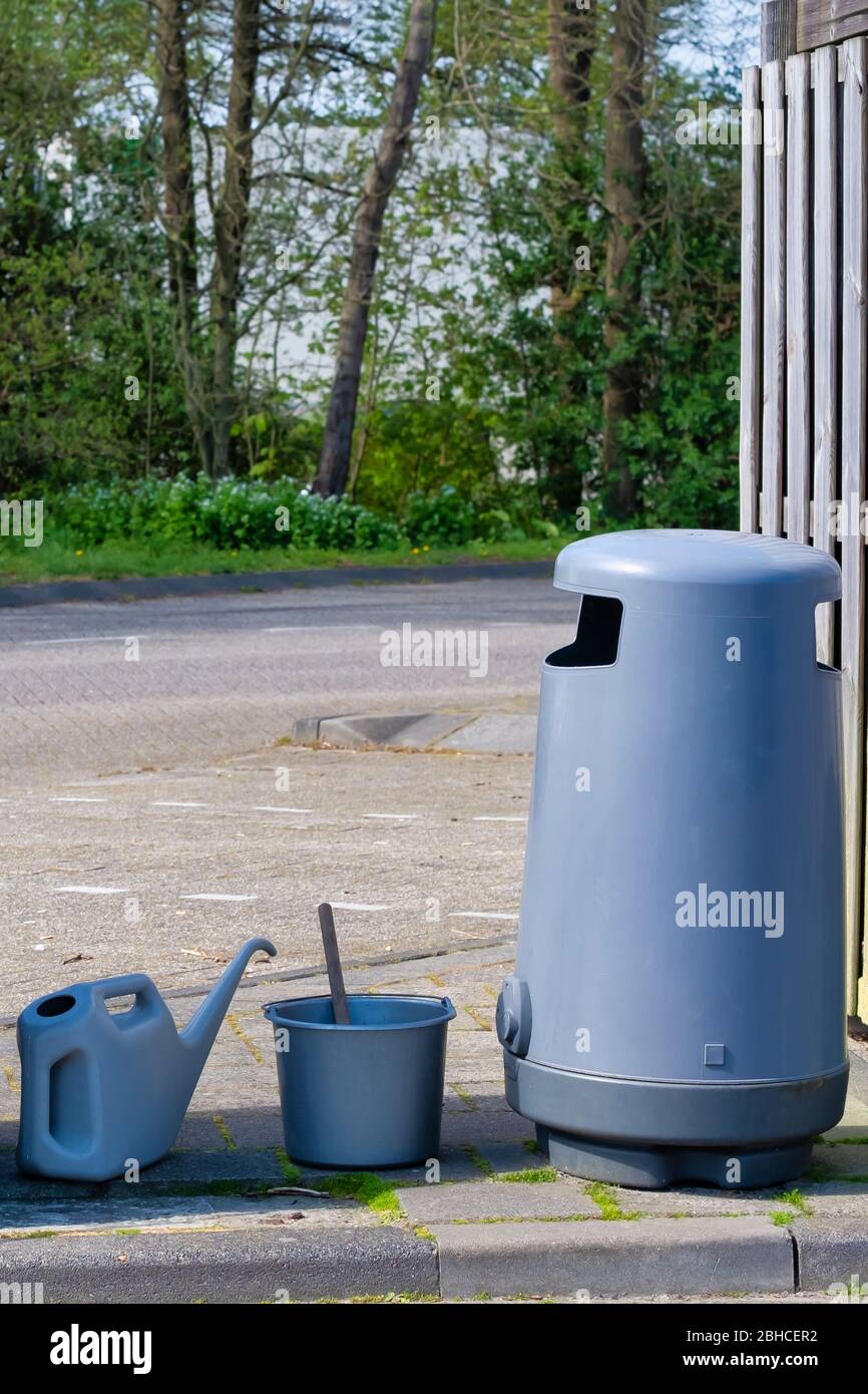 A garbage can, bucket and a water jug to wash the windows at a gas