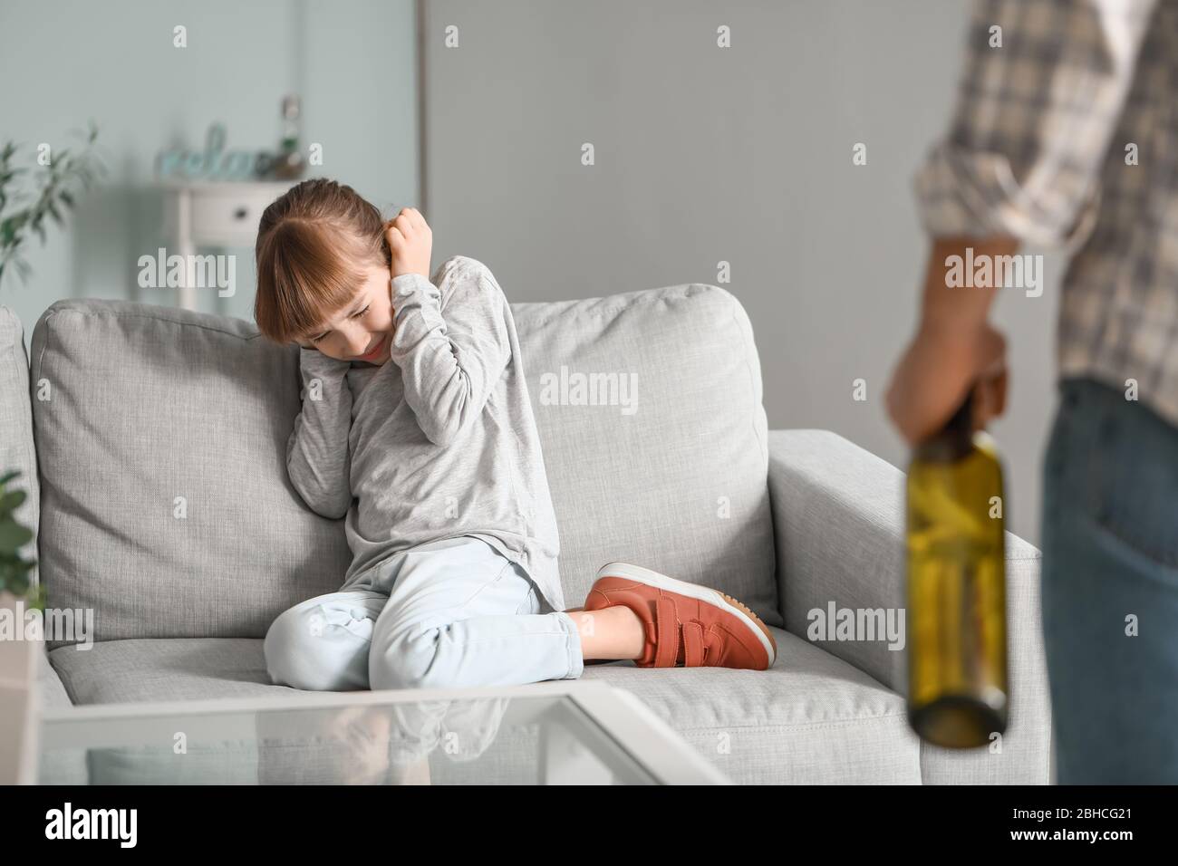 Drunk father standing in front of scared daughter at home Stock Photo