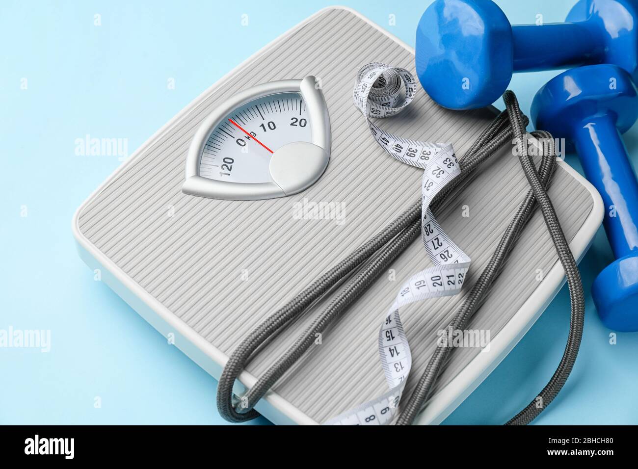 Weight scales with measuring tape, jumping rope and dumbbells on color ...