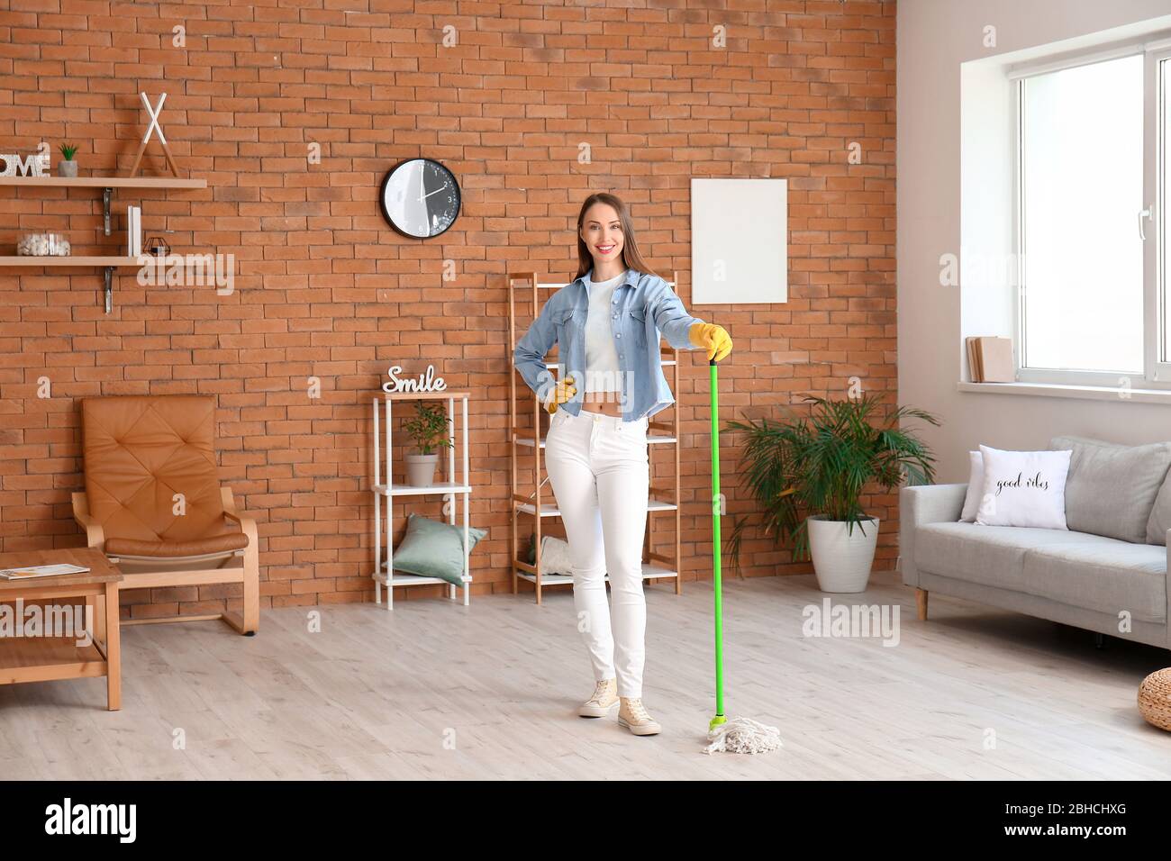 Young woman mopping floor in room Stock Photo